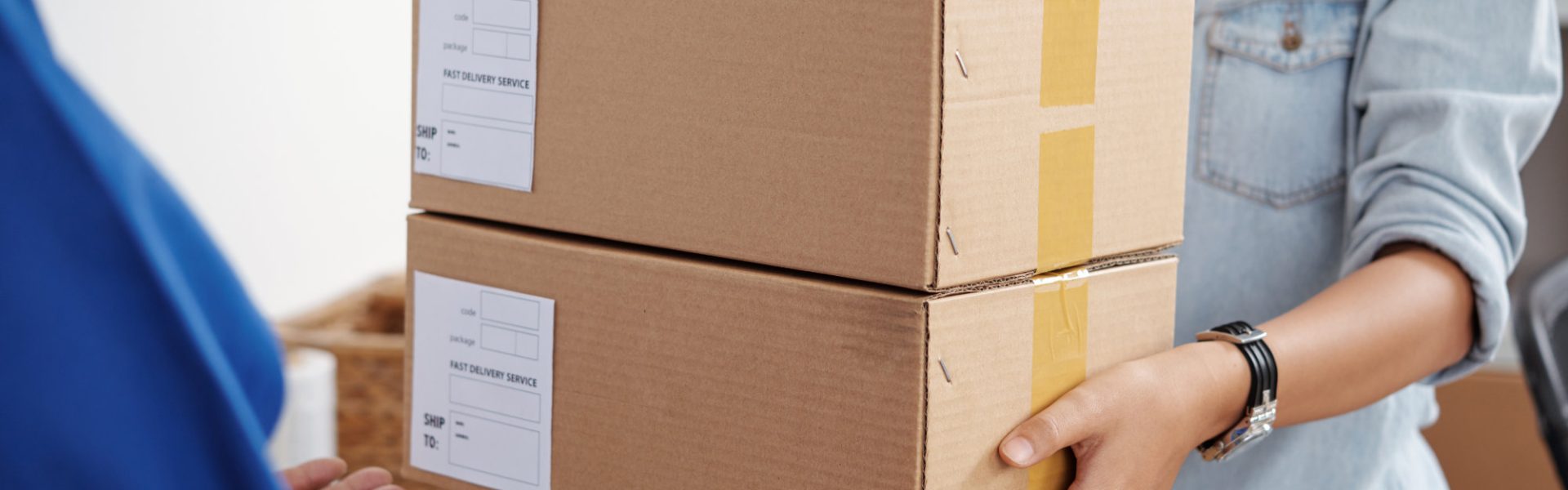 Young postwoman giving package to the man at post office